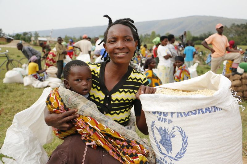 Maria and her baby Remi, after collecting food at the new site in Oruchinga. WFP/Claire Nevill