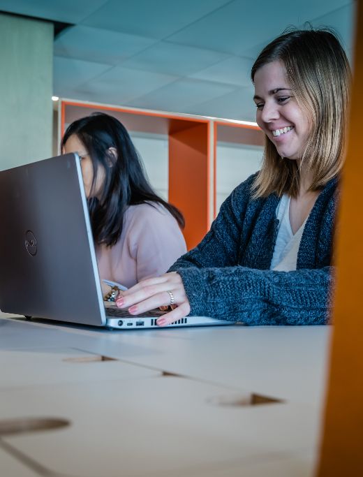 A woman smiling and typing on her laptop