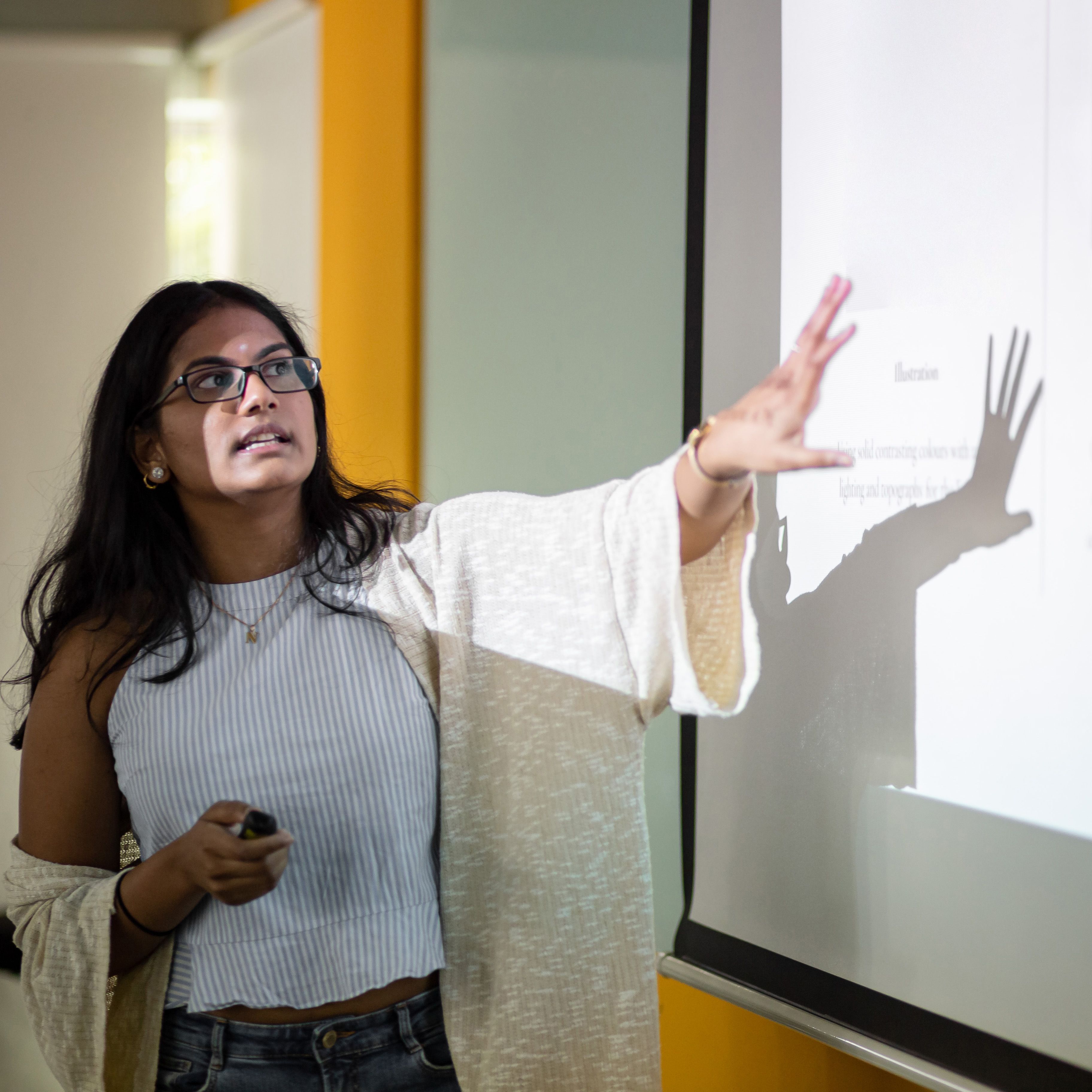 Asian college student is making a presentation in front of projector screen