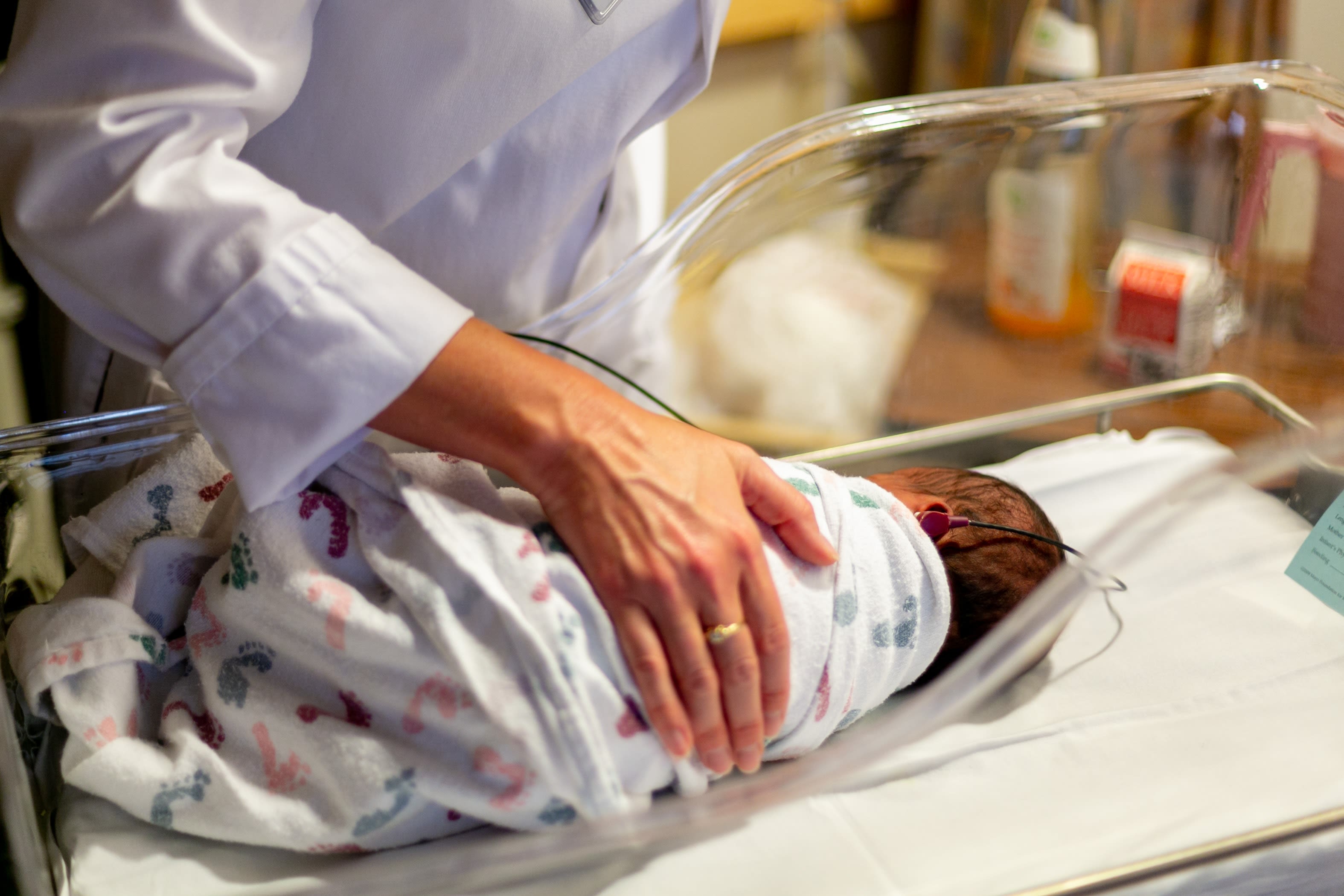 A new born baby lays in a hospital cot