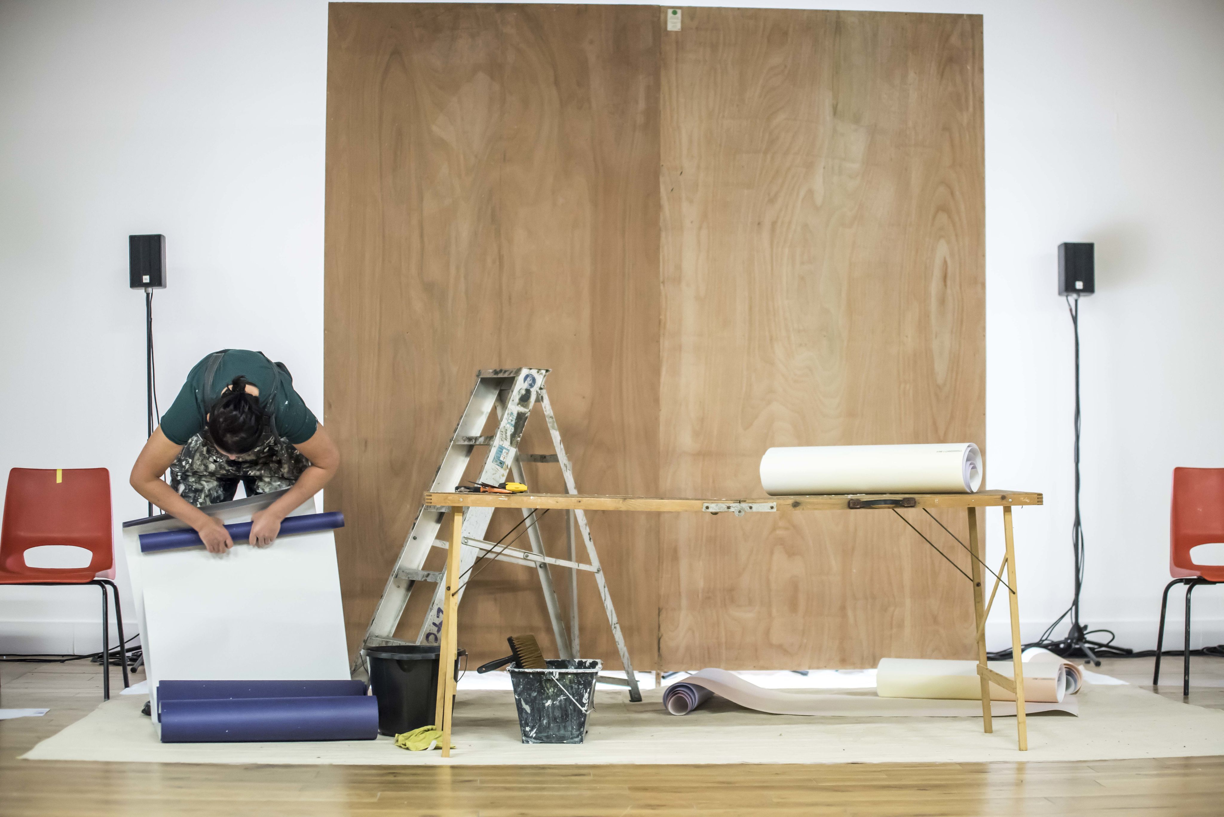 a woman rolls up a roll of wallpaper