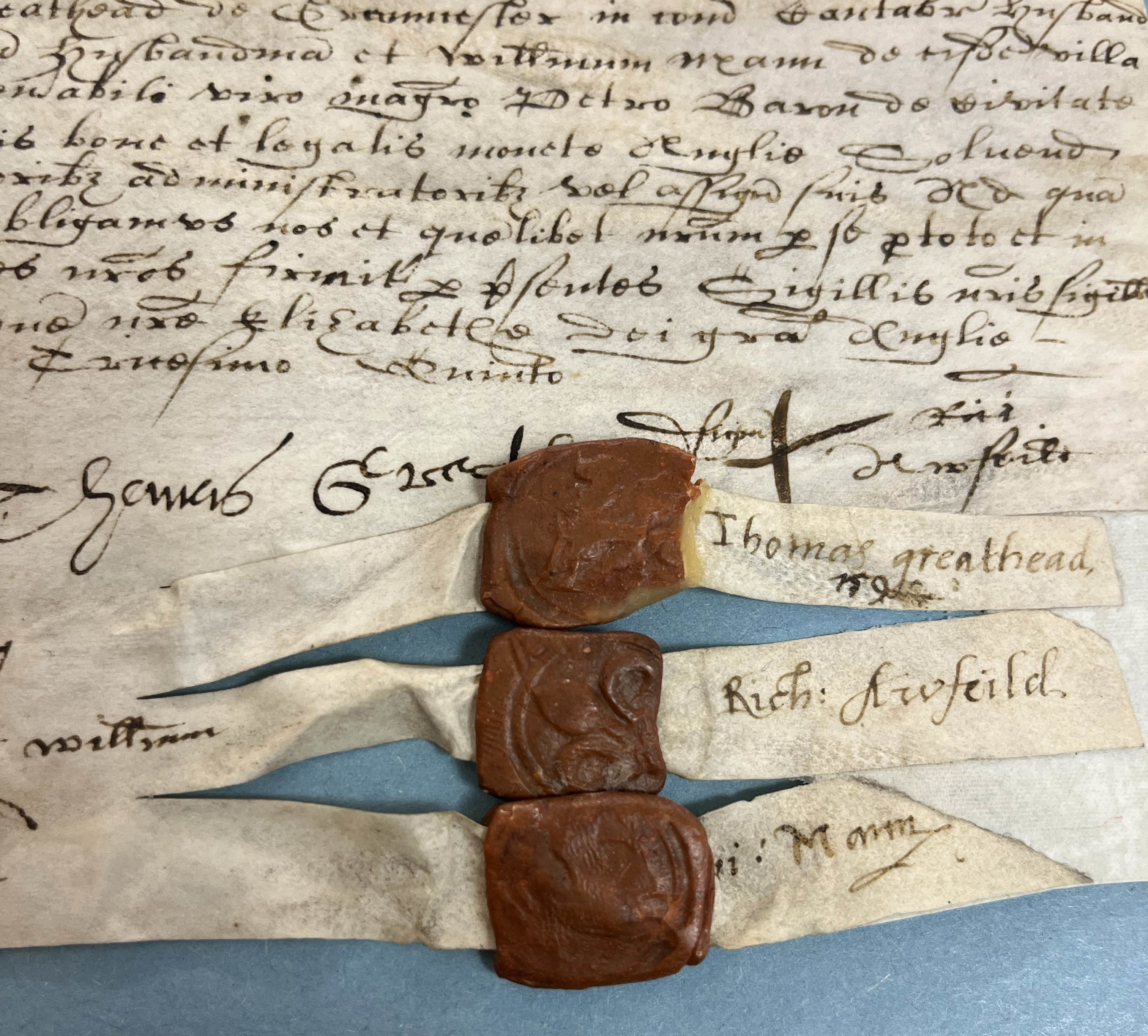 A photograph of three red wax seals at the bottom of a manuscript document.