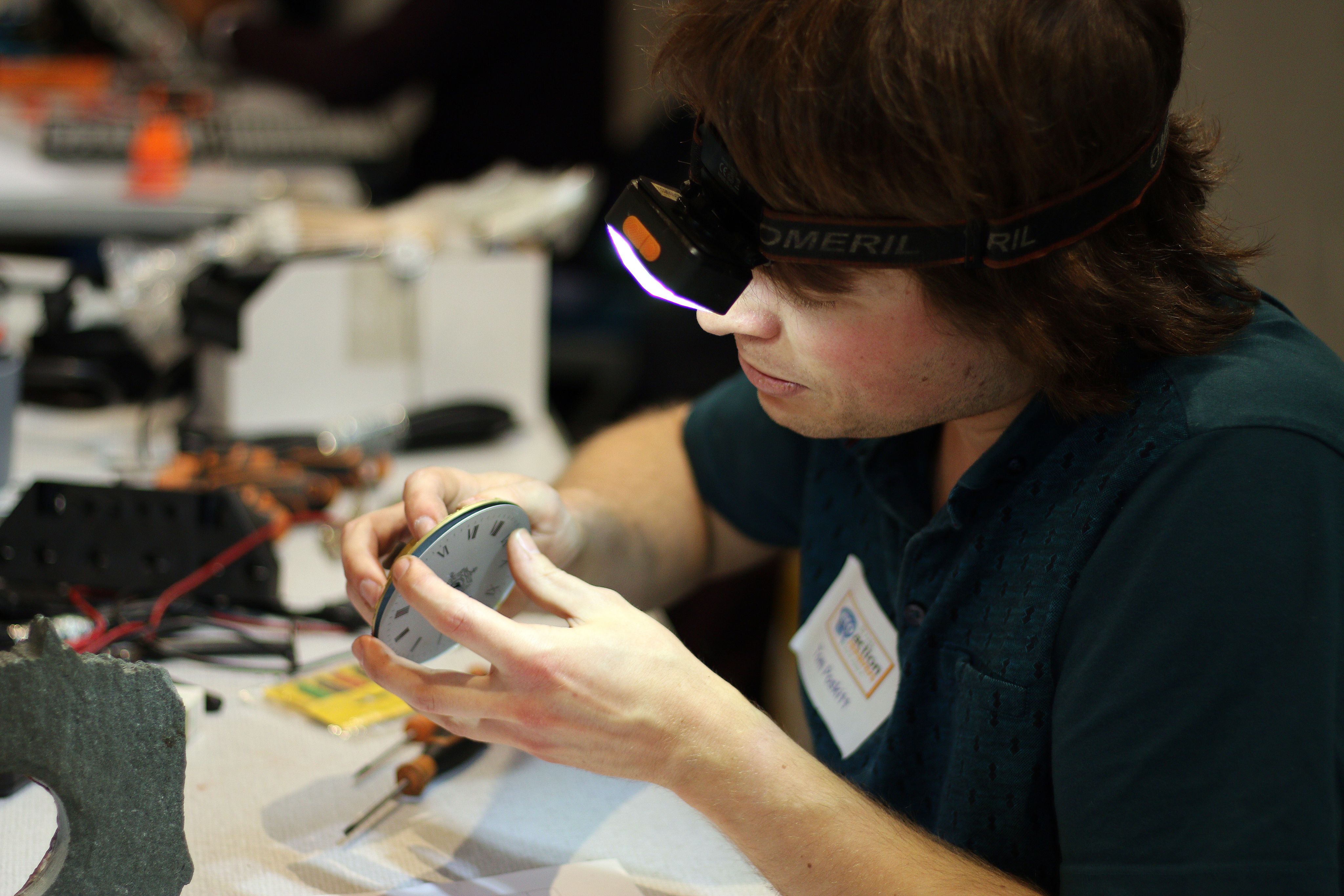 Volunteer repairs a clock