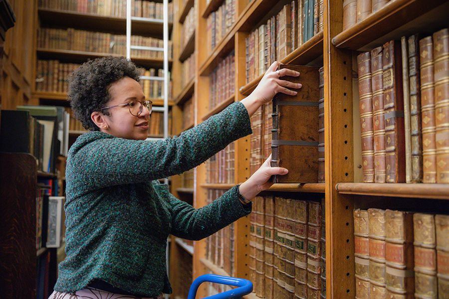Mathelinda Nabugodi taking book off shelf