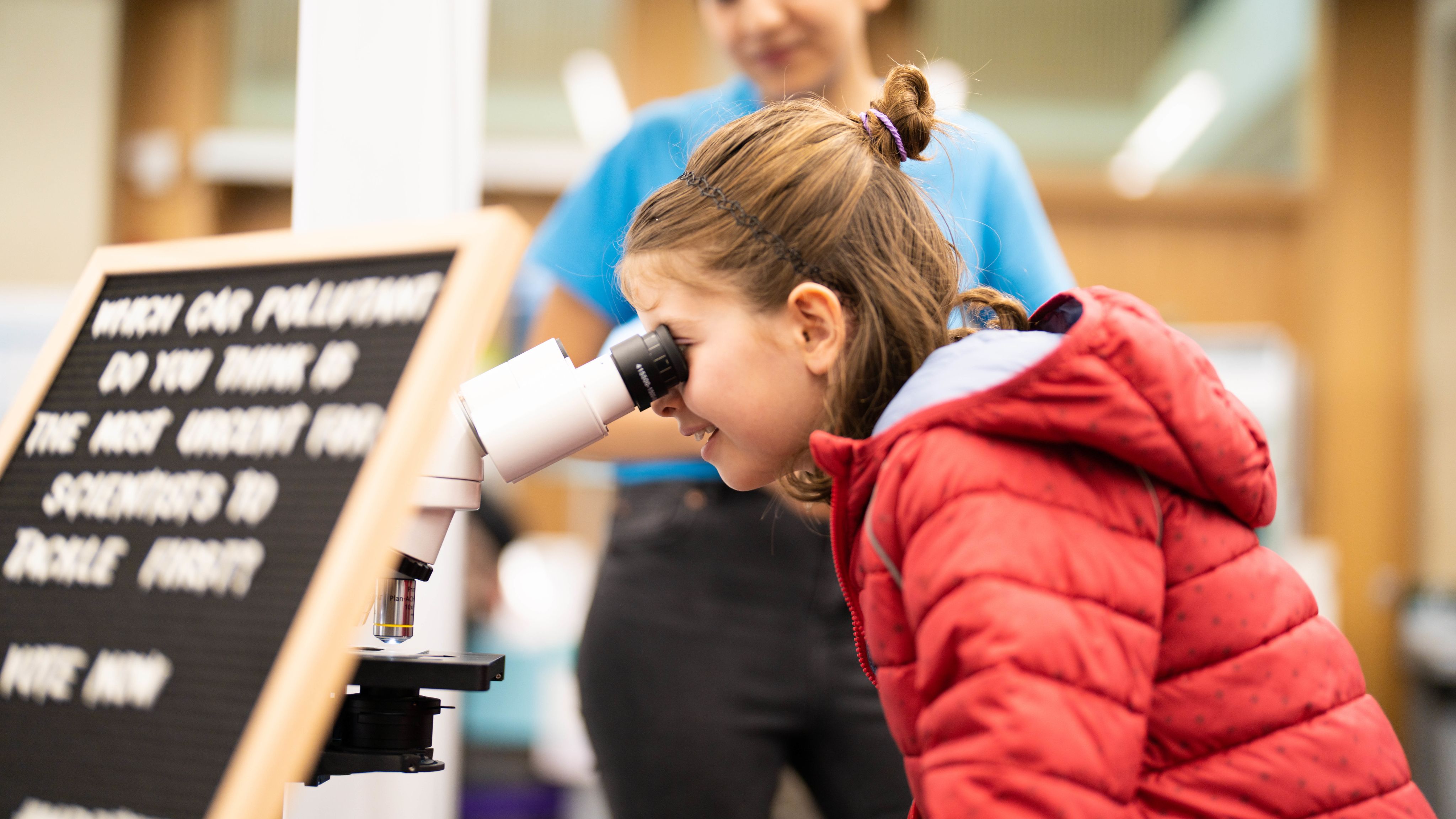 A young girl looks through a microscope
