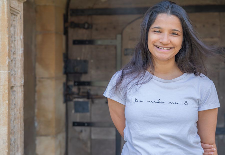 Ashna Biju in the grounds of Caius College, standing with old door behind her