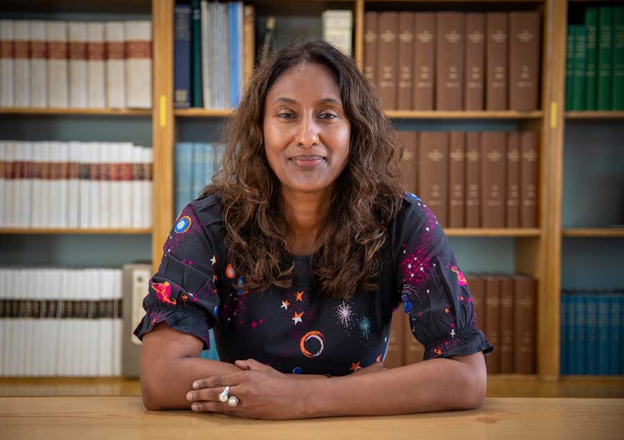 Hiranya Peiris in front of a bookcase