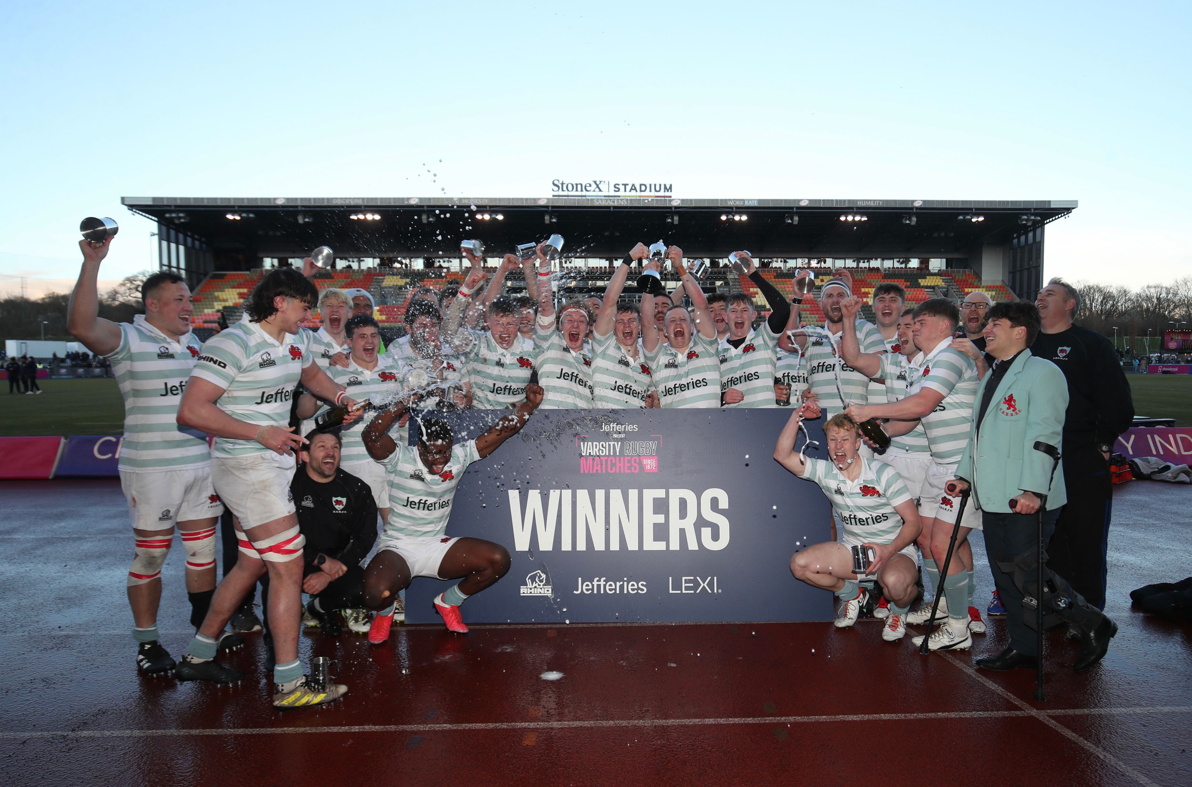 The men's rugby team cheering and holding up the winning trophy