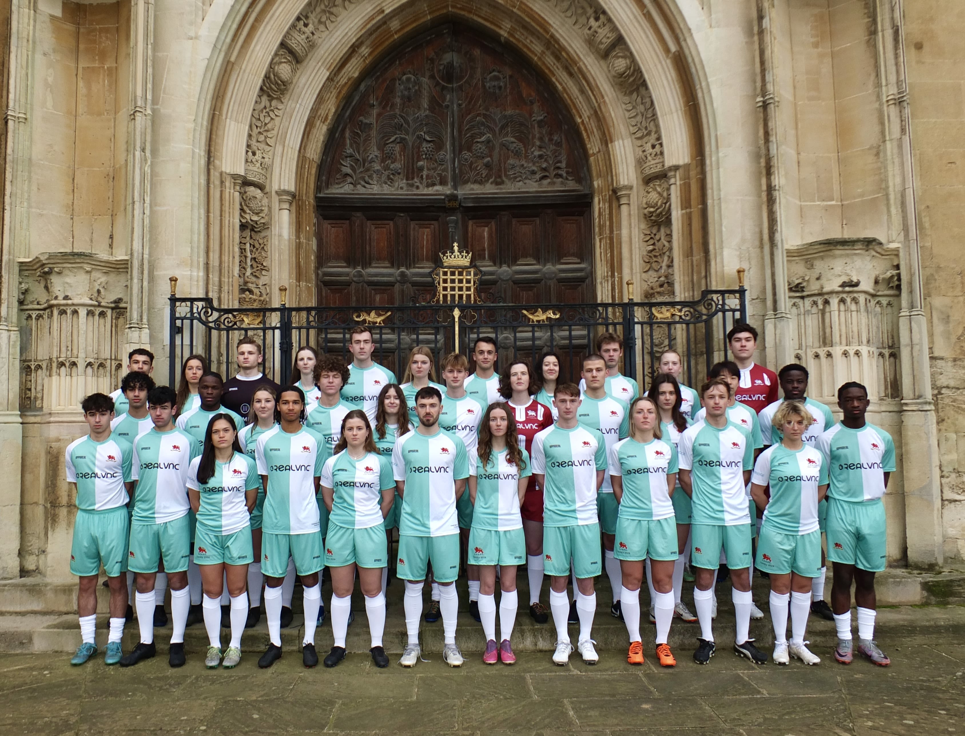 The men's and women's football teams combined, standing in their football kit