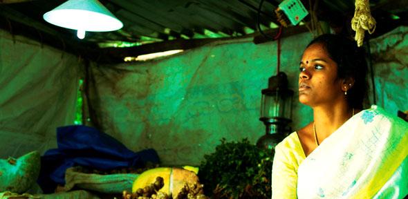 A vegetable vendor uses a solar lamp to light her stall