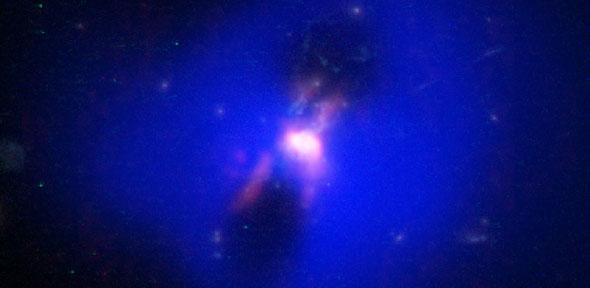 Composite image showing how powerful radio jets from the supermassive black hole inflated huge bubbles in the hot, ionized, gas surrounding the galaxy. Credit: ALMA