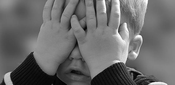 Child with hands over face - children may be at risk by too much focus on COVID-19