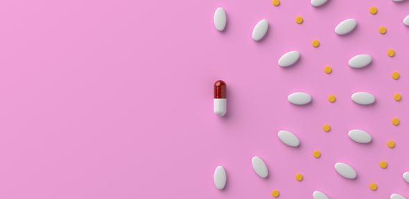 Pills and a capsule on pastel pink colored background. 3D rendered image.