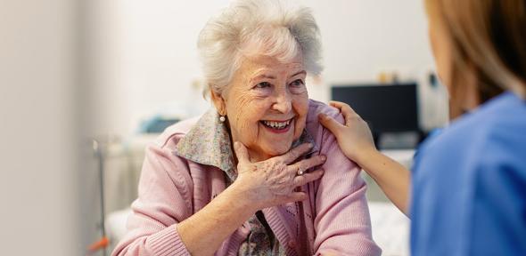 Smiling elderly woman speaking to a healthcare worker