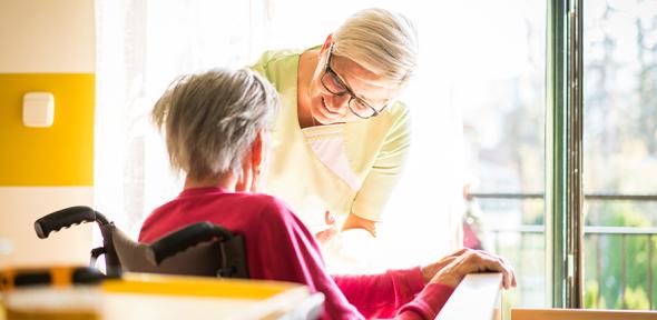 Nurse taking care of elderly sick woman in wheelchair 