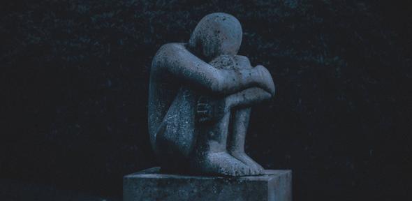 Statue of a figure hugging its knees
