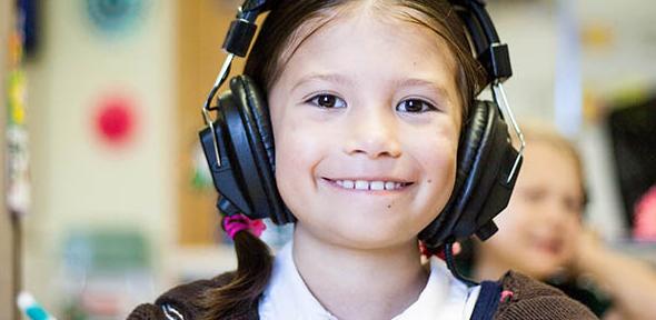 Girl using headphones in a classroom