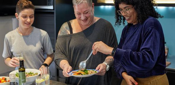 A group of people standing around a table with plates of food