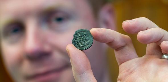 Prof. Rory Naismith holding a silver Byzantine coin in the Fitzwilliam Museum, Cambridge. Photo: Adam Page