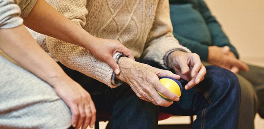 Woman touching the arm of an elderly man holding a juggling ball