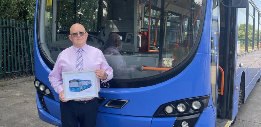 Man stands in front of a blue bus