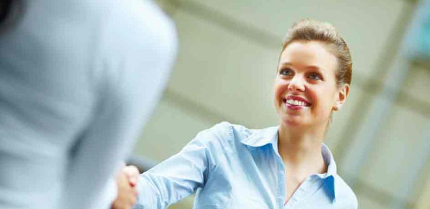 Happy young business woman shaking hands with another female