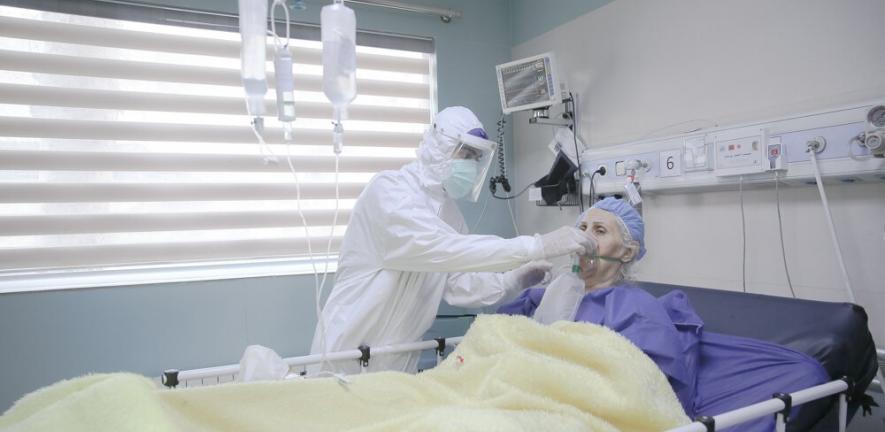 A clinician helping a COVID-19 patient with an oxygen mask in a hospital in Iran