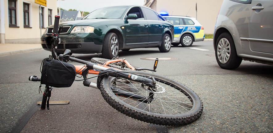 Bicycle lying in the road in front of a car