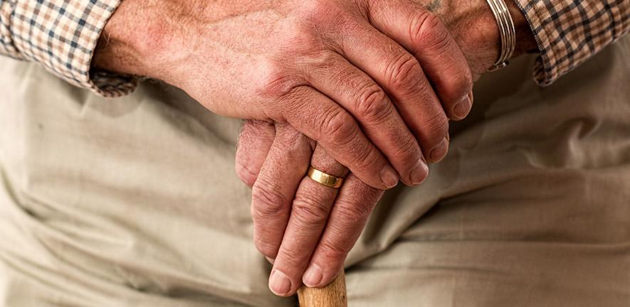 Hands of an elderly man with walking stick