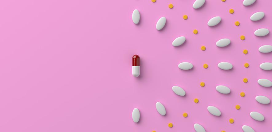 Pills and a capsule on pastel pink colored background. 3D rendered image.