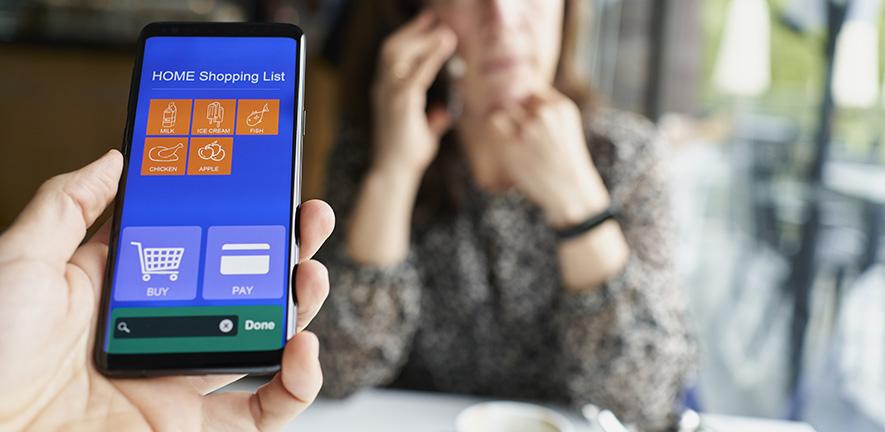 Hand holding a smartphone showing an online supermarket