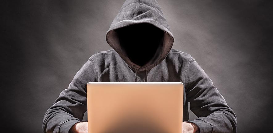 Hooded figure using a laptop computer