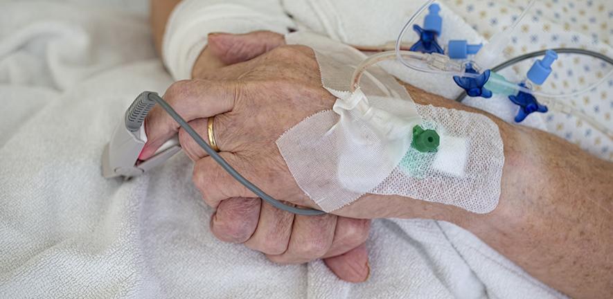 Hands of senior man with cannulae and band-aid being in intensive care