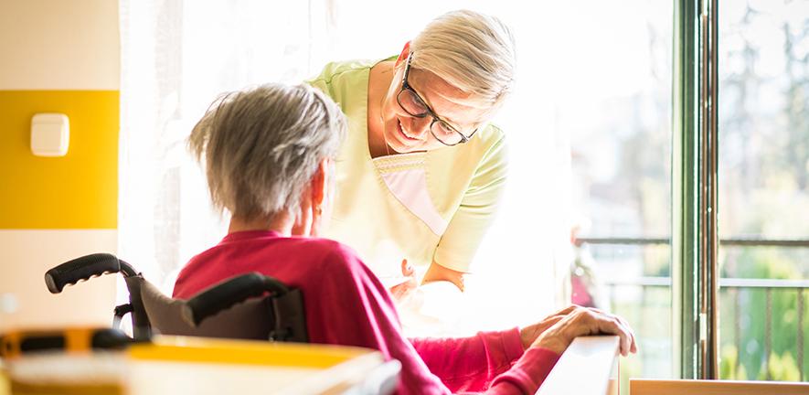 Nurse taking care of elderly sick woman in wheelchair 