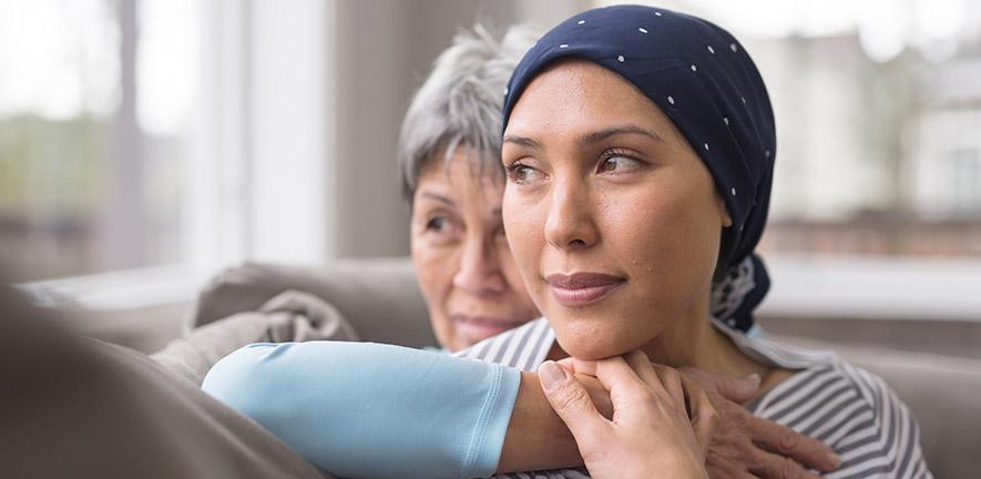 An Asian woman in her 60s embraces her mid-30s daughter who is battling cancer - stock photo