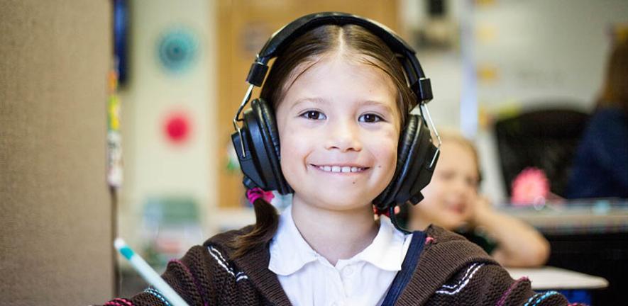 Girl using headphones in a classroom