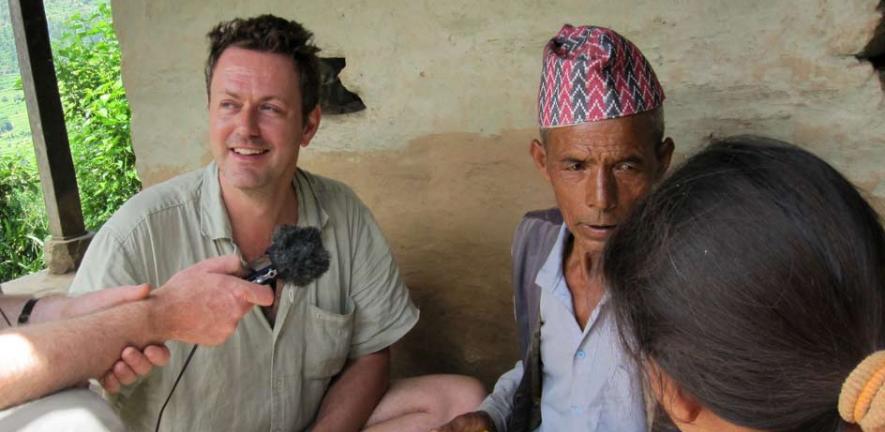 Mark Turin returning a copy of the grammar of the Thami language to one of his principal research partners and language teachers. Local intellectual Man Bahadur Thami and his daughter on the right. Cokati, Sindhupalcok, Nepal, August 2012. 