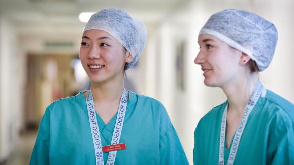 Two students in medical gowns smiling