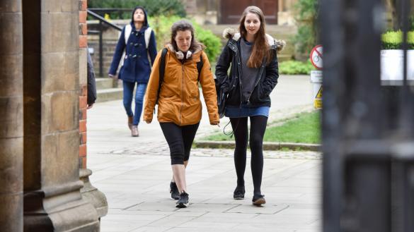 Two students walking across cobbles