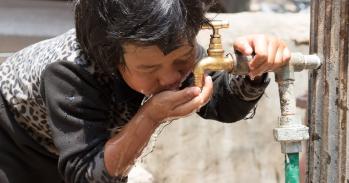 A young child drinks from a water tap