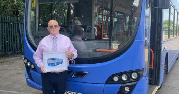 Man stands in front of a blue bus