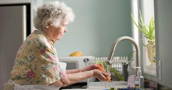 Woman in purple and white floral shirt washing a carrot