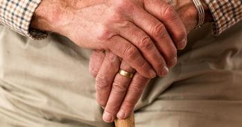 Hands of an elderly man with walking stick