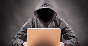 Hooded figure using a laptop computer