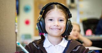 Girl using headphones in a classroom