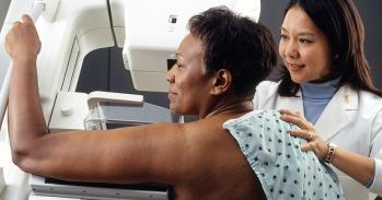 Female doctor standing near woman patient doing breast cancer scan