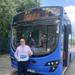 Man stands in front of a blue bus