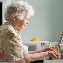 Woman in purple and white floral shirt washing a carrot