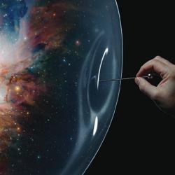 A pin being pushed into a bubble, in which there is an image of the Universe