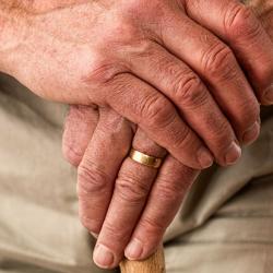 Hands of an elderly man with walking stick